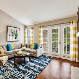 Living area of premium model home with large windows and patio overlooking the pond.